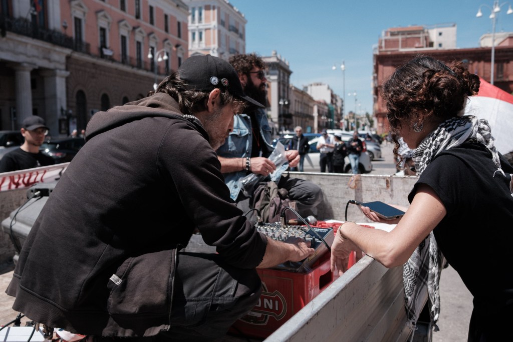 Sound check ahead of the 18 May 2026 march: a technician adjusts the mixer on a beer crate, Bari.