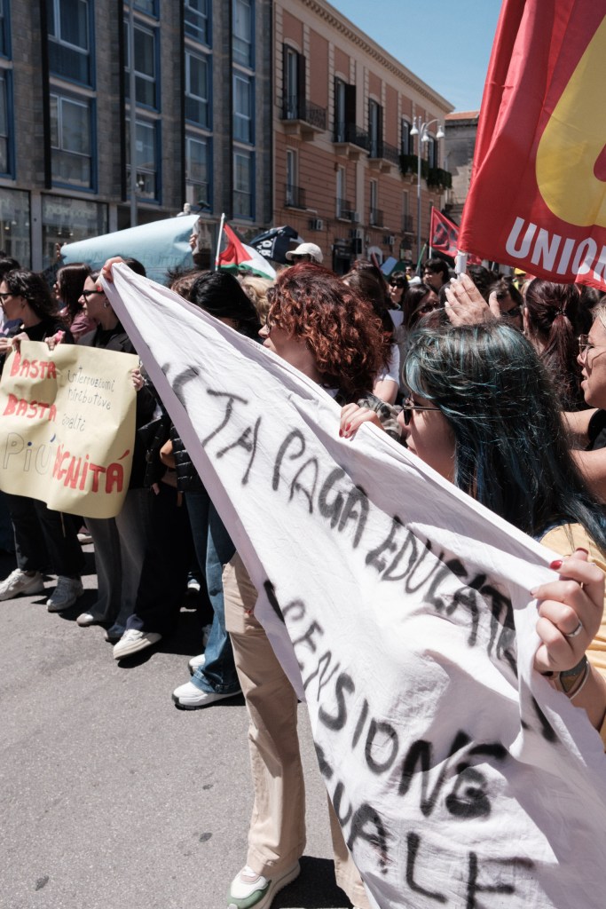 Marchers hold up a white banner about pensions during the Bari march.