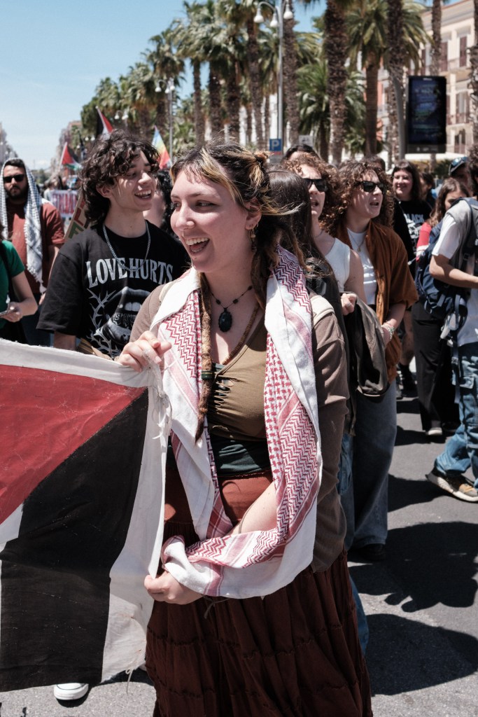 A young marcher with a keffiyeh around her neck smiles amid the crowd.