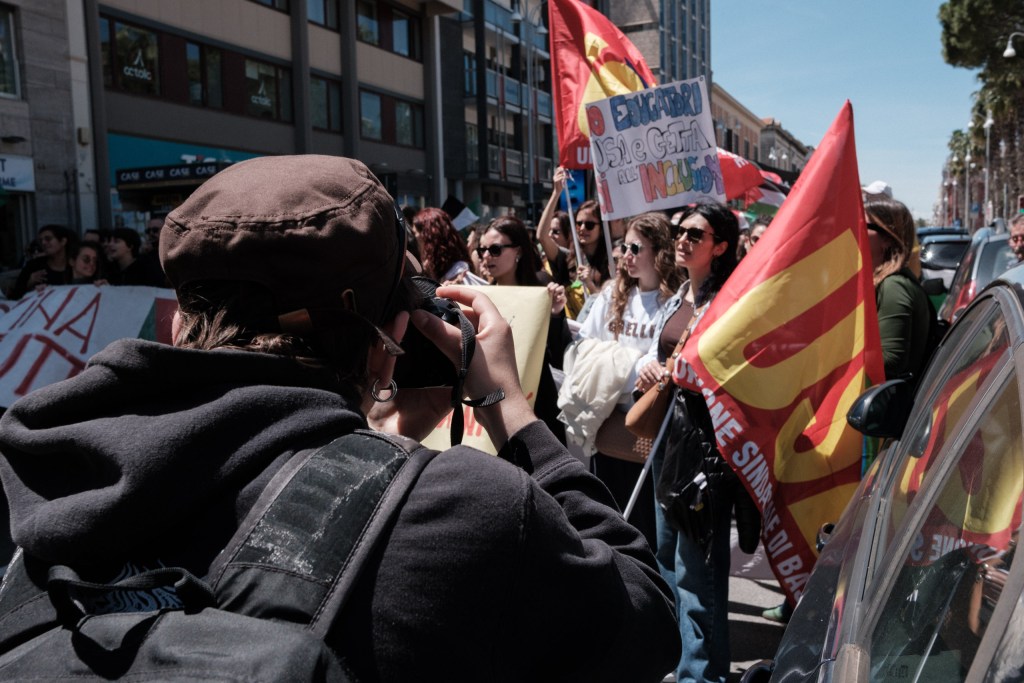 A marcher photographs a group holding a "No disposable educators" sign during the march.