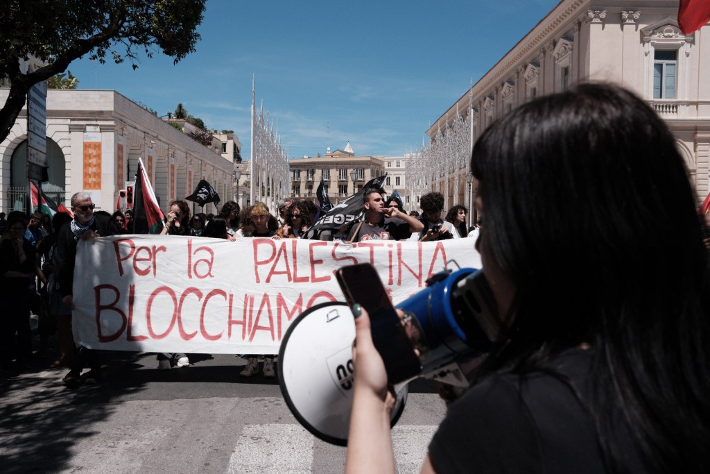 The march seen from the side, a "For Palestine we block" banner in front of a white historic building.