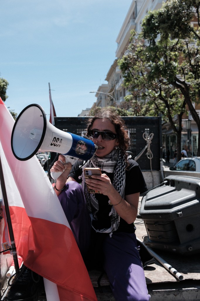 A marcher shouts into a megaphone while holding her phone, amid the crowd.