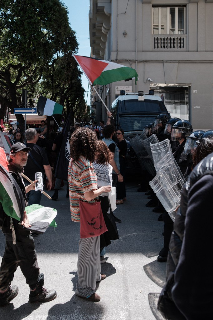 Un manifestante solleva una bandiera palestinese sopra gli scudi dei Carabinieri, corteo del 18 maggio 2026.