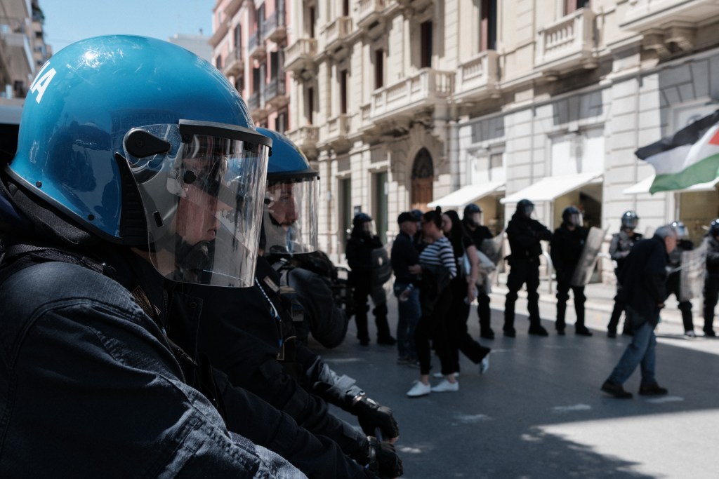 Close-up of officers with helmets and visors lowered, lined up along the street.