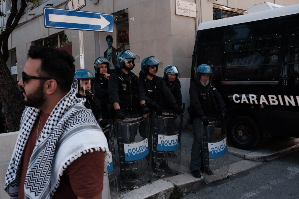 A line of officers with "Polizia" shields lined up in front of a Carabinieri van, Via Calefati.